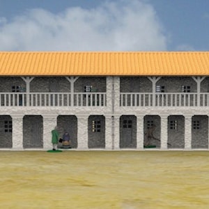 Op de afbeelding: Een 3D-geprint model van een gebouw met twee verdiepingen met een witte gevel, rode accenten en een terracotta dak. Het gebouw heeft een balkon op de tweede verdieping en een reeks gebogen deuropeningen op de begane grond. Het gebouw is geplaatst tegen een achtergrond van een blauwe lucht met witte wolken.