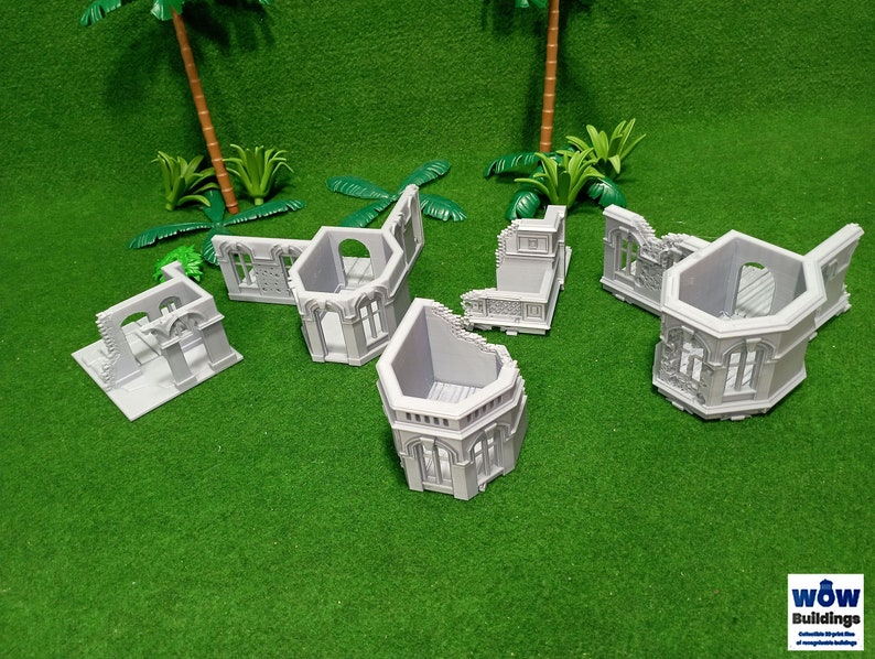 May include: A set of six gray plastic model building ruins. The ruins are in various shapes and sizes, and some have windows and doors. The ruins are on a green surface.