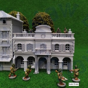 Puede incluir: Un conjunto de edificios en miniatura grises con detalles arquitect&oacute;nicos, incluyendo balcones, contraventanas y puertas arqueadas. Varios soldados en miniatura camuflados est&aacute;n posicionados alrededor de los edificios. La escala es de 15 mm.