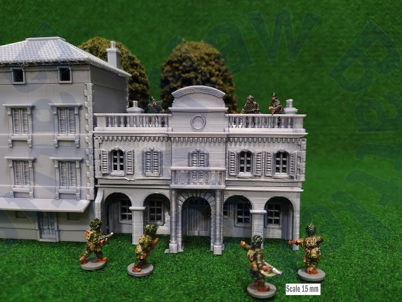 Puede incluir: Un conjunto de edificios en miniatura grises con detalles arquitect&oacute;nicos, incluyendo balcones, contraventanas y puertas arqueadas. Varios soldados en miniatura camuflados est&aacute;n posicionados alrededor de los edificios. La escala es de 15 mm.