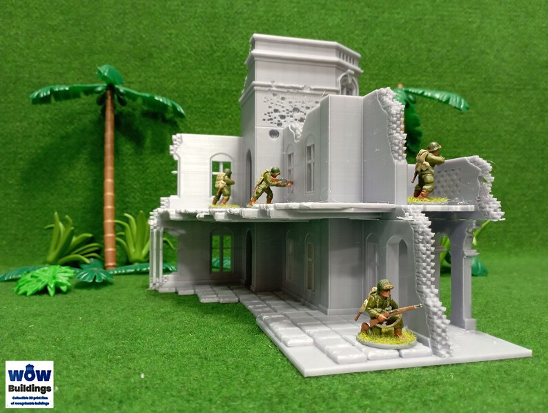 May include: A gray, ruined building with a tower, partially destroyed, with four miniature figures in military uniforms standing on the roof and inside the building. The building is set against a green background.