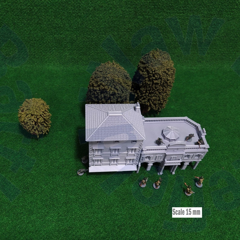 Puede incluir: Un edificio gris en miniatura con tejado de tejas, rodeado de peque&ntilde;os &aacute;rboles y figuras. El texto "Scale 15 mm" es visible. La escena est&aacute; sobre una superficie verde, para un juego de mesa.