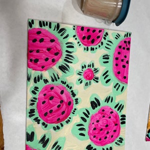 Può includere: Un dipinto su tela con un motivo di fette di anguria rosa e nere su uno sfondo verde chiaro e crema.