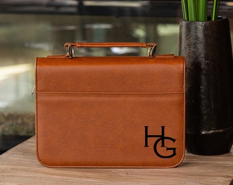 May include: A brown leather Bible cover with a silver handle and the initials "HG" embossed on the front.