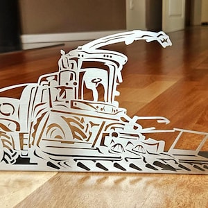 May include: A silver metal cutout of a combine harvester. The detailed artwork depicts the machine's cab, wheels, and harvesting components. The piece is designed to stand upright, showcasing the agricultural theme.