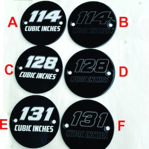 May include: Six black round metal engine covers with white lettering. The covers are engraved with different cubic inch measurements: 114, 128, and 131. The covers are labeled with letters A through F. The text "BILLET POWDER COATED - ENGRAVED" is at the bottom of the image.