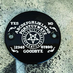 May include: Black circular ouija board with white lettering. The board features the alphabet, numbers 1-9 and 0, the words "YES", "NO", and "GOODBYE", and a pentagram.