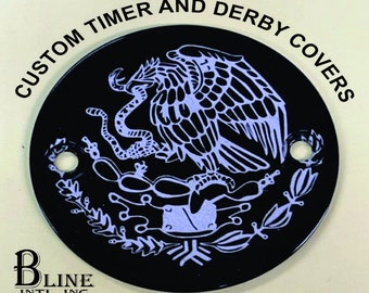 May include: Black round motorcycle cover with a white outline of the Mexican coat of arms featuring an eagle perched on a cactus with a snake in its beak. The text "CUSTOM TIMER AND DERBY COVERS" is written around the edge of the cover.