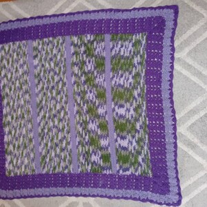 May include: A purple and green crocheted blanket with a scalloped border.