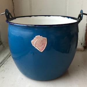 May include: Blue enamel bucket with a white rim and a silver sticker with a rooster logo. The sticker says "Qualita" and "Made in Italy".