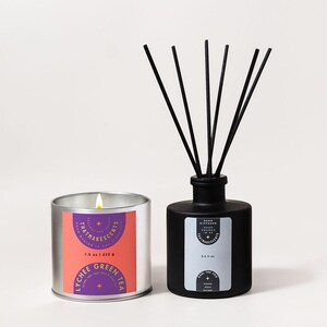 May include: A lit silver candle and a black reed diffuser. The candle has a label with the text "Lychee Green Tea" and "That Makes Scents". The diffuser has black reeds and a label with the text "Carl the Fog". The candle is 7.5 oz.