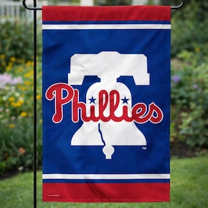 May include: A blue, red, and white Phillies garden flag. The flag features the Phillies logo, a white Liberty Bell with the word "Phillies" in red script. The top and bottom borders are red.