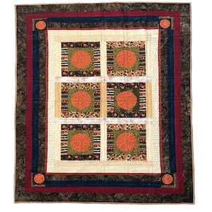 Può includere: Una trapunta fatta a mano con un disegno centrale di sei quadrati, ciascuno con un cerchio arancione. La trapunta ha uno sfondo color crema con un bordo marrone scuro, rosso e blu navy. Un accogliente elemento di arredo.