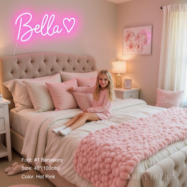 K&ouml;nnte beinhalten: Ein leuchtendes, pinkfarbenes Neonschild mit dem Namen Bella in Schreibschrift, gefolgt von einem Herzsymbol. Das Schild ist 100 cm breit, im Barcelony-Schriftstil gestaltet und strahlt ein helles Licht an der Wand &uuml;ber dem Bett aus.