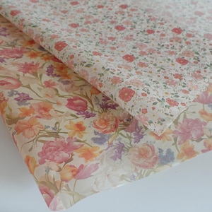 May include: Two sheets of floral wrapping paper. One sheet has a dense pattern of small red and pink flowers on a white background. The other sheet has a larger floral design with pink, orange, and purple flowers on a cream background.