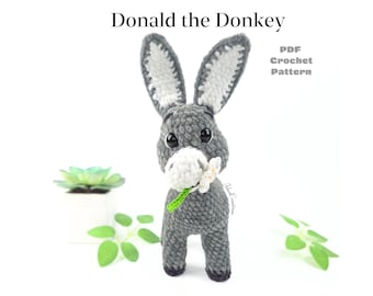 May include: A crocheted donkey toy in shades of gray, white, and black, holding a white flower with a green stem. The donkey has large, expressive eyes and long ears. Text at the top reads "Donald the Donkey" and "PDF Crochet Pattern".