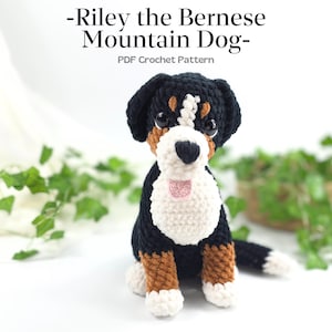 May include: A crocheted Bernese Mountain Dog, featuring black, white, and brown yarn. The dog has a white chest, brown legs, and a black head with brown accents. The text "-Riley the Bernese Mountain Dog- PDF Crochet Pattern" is at the top.