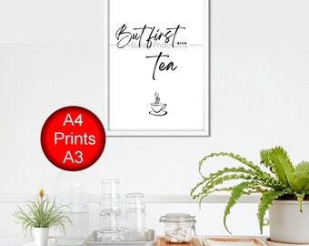 May include: A white framed print with black text that reads "But first, tea" with a stylized image of a teacup and steam. The print is hanging on a white wall.