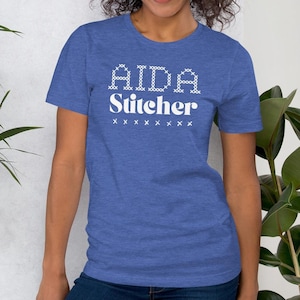 May include: A blue t-shirt with white text that reads "AIDA Stitcher" with a row of white "x"s below the text.