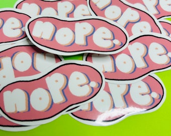 May include: A pile of pink and white stickers with the word "nope" written in a bold, cartoon font. The stickers are shaped like a speech bubble.