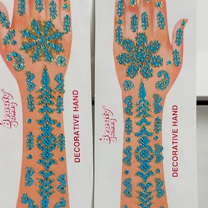 Puede incluir: Dos hojas de tatuajes decorativos para manos con un diseño azul y dorado. Las hojas están etiquetadas como "Beauty Swag" y "Mano decorativa".