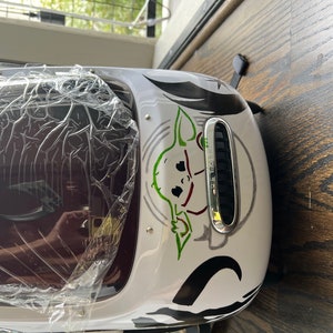 Puede incluir: Mochila blanca con un gr&aacute;fico negro y verde de un personaje de la franquicia Star Wars. El personaje es un extraterrestre verde con orejas grandes y una expresi&oacute;n traviesa. La mochila tiene una ventana de pl&aacute;stico transparente en la parte delantera.