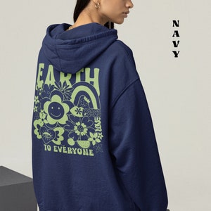 May include: A navy blue hooded sweatshirt with a green graphic on the back that says "Earth Peace Love To Everyone" with a smiley face and flowers.