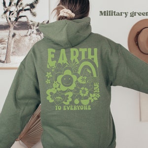 May include: A military green hoodie with a green graphic print on the back that says "EARTH TO EVERYONE" with a rainbow, flowers, and a smiley face.