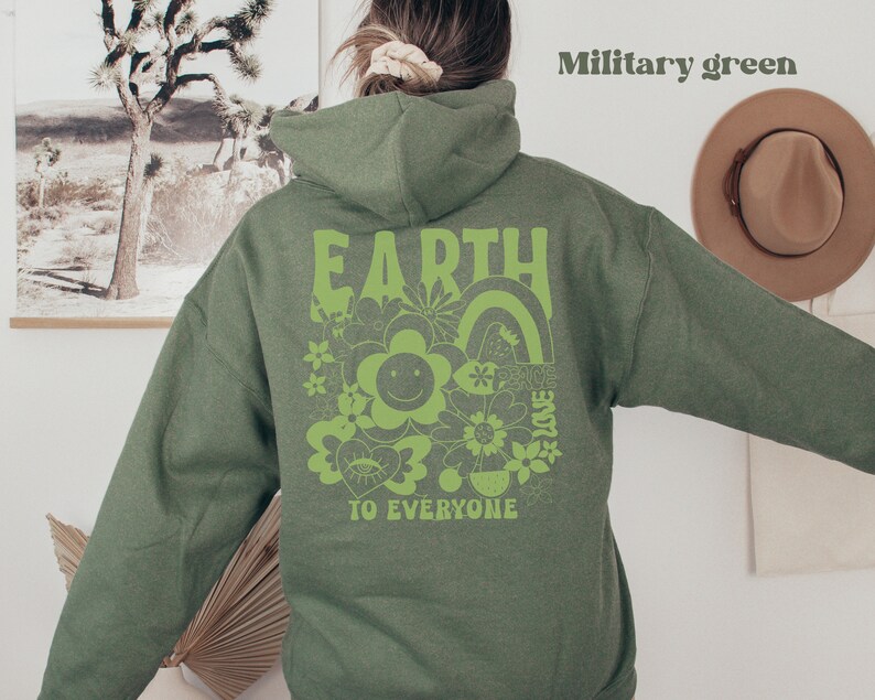 May include: A military green hoodie with a green graphic print on the back that says "EARTH TO EVERYONE" with a rainbow, flowers, and a smiley face.