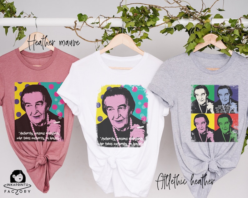 May include: Three t-shirts with a pop art style image of a woman with a quote about authority. The t-shirts are in heather mauve, white, and athletic heather.