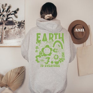 May include: Gray hooded sweatshirt with a green graphic print on the back. The graphic features the word "EARTH" in large letters, a smiling flower, and the text "TO EVERYONE".