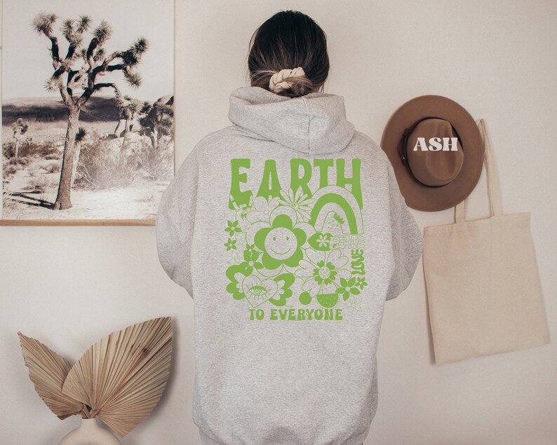 May include: Gray hooded sweatshirt with a green graphic print on the back. The graphic features the word "EARTH" in large letters, a smiling flower, and the text "TO EVERYONE".