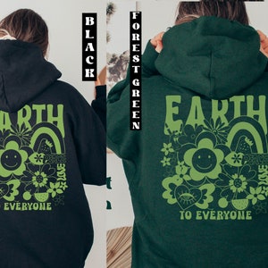 May include: A black and forest green hoodie with a green graphic print on the back. The graphic features the word "EARTH" in large letters, a smiley face flower, and the words "PEACE LOVE TO EVERYONE".