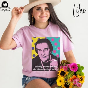 May include: A lilac t-shirt with a pop art style image of a woman with a quote: "Authority poisons everybody who takes authority on himself."