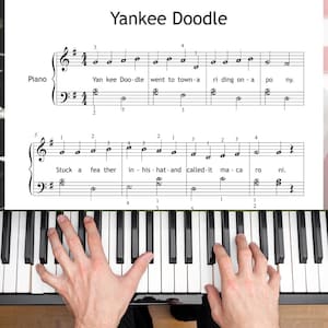 May include: Sheet music for "Yankee Doodle" with piano notes and lyrics. The text "Yankee Doodle" is at the top. A person's hands are playing the piano keys. The piano keys are black and white.