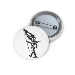 May include: A round pin-back button featuring a black and white graphic of a figure in a suit walking while holding a large flag. The design is centered on a white background. The back of the button is metallic silver with a horizontal pin mechanism.