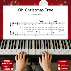 May include: A piano score for "Oh Christmas Tree" (O Tannenbaum) with musical notes and lyrics. The piano keyboard is visible, with hands positioned to play. Additional text includes "Grade I", "Piano Score", "+ MP3", "+ Video", "+ Bonus", "Colored Notes", and "Letter Notes".