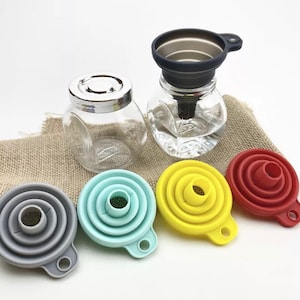 May include: Set of five collapsible funnels, including one stainless steel funnel. The funnels are grey, blue, yellow, and red. The funnels are made of silicone and are designed to fold flat for easy storage.