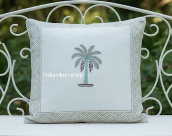 May include: A square throw pillow with a white centre panel featuring an embroidered green palm tree. The pillow has a wide border with a repeating geometric pattern in light green and white. The text Indianlinenshop is visible on the front.