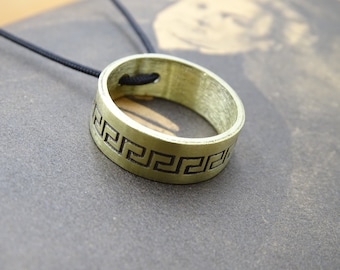 May include: A gold-colored ring pendant with a black cord. The ring has a Greek key design engraved around the edge.