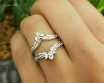 Puede incluir: Un anillo de oro blanco con un diseño en forma de V y pequeños diamantes engastados en la banda.