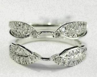 Puede incluir: Un engaste de anillo de plata con un delicado diseño de hoja, con pequeños diamantes engastados en el metal. El anillo está abierto en el centro, diseñado para sujetar una piedra central.