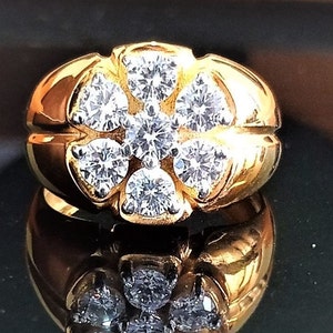 May include: A gold ring with a cluster of round diamonds set in a flower shape. The ring has a textured band.