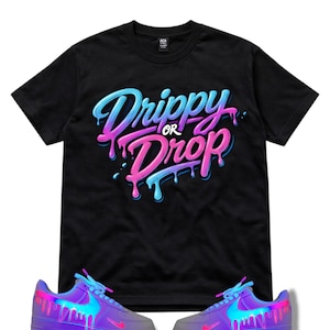 May include: Black crew neck t-shirt with the text "Drippy or Drop" in blue and pink dripping font. Below the shirt are purple sneakers with blue and pink dripping paint designs.