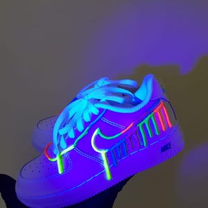 Puede incluir: Zapatillas blancas de ca&ntilde;a baja con detalles de pintura de color verde ne&oacute;n, azul, rosa y rojo. La pintura gotea por el lateral de la zapatilla.