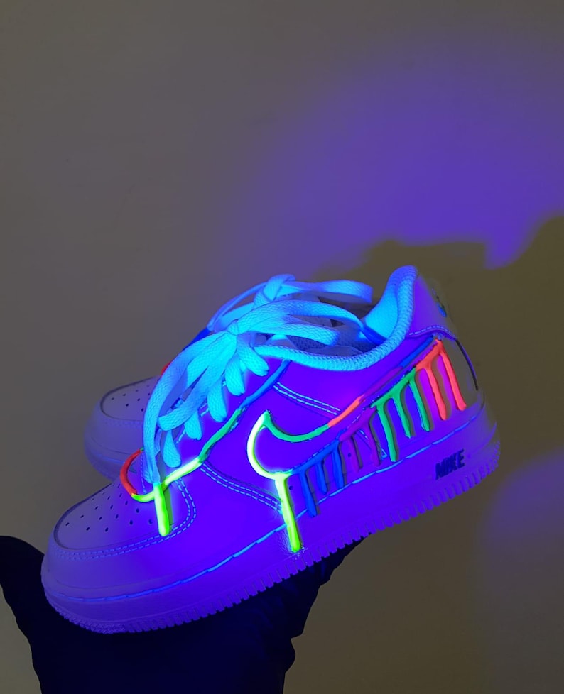 Puede incluir: Zapatillas blancas de ca&ntilde;a baja con detalles de pintura de color verde ne&oacute;n, azul, rosa y rojo. La pintura gotea por el lateral de la zapatilla.