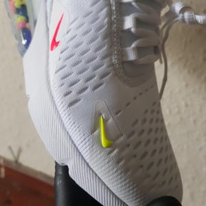 May include: White athletic shoe with a textured upper. Features a neon yellow swoosh logo on the side and a red swoosh logo on the upper. The shoe has white laces and a white sole.