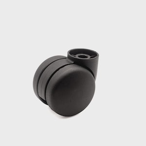 May include: A black plastic twin-wheel caster with a smooth, rounded exterior and a central mounting socket. The caster features two side-by-side wheels connected by a sturdy housing, designed for mobility on furniture or office chairs.
