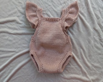 May include: A knitted baby onesie with ruffled sleeves in a light pink color.