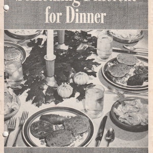 May include: Black and white vintage cookbook cover titled "Something Different for Dinner." The image shows a table setting with plates of food, glasses of water, and a candle. The author's name is Mary Lee Taylor.